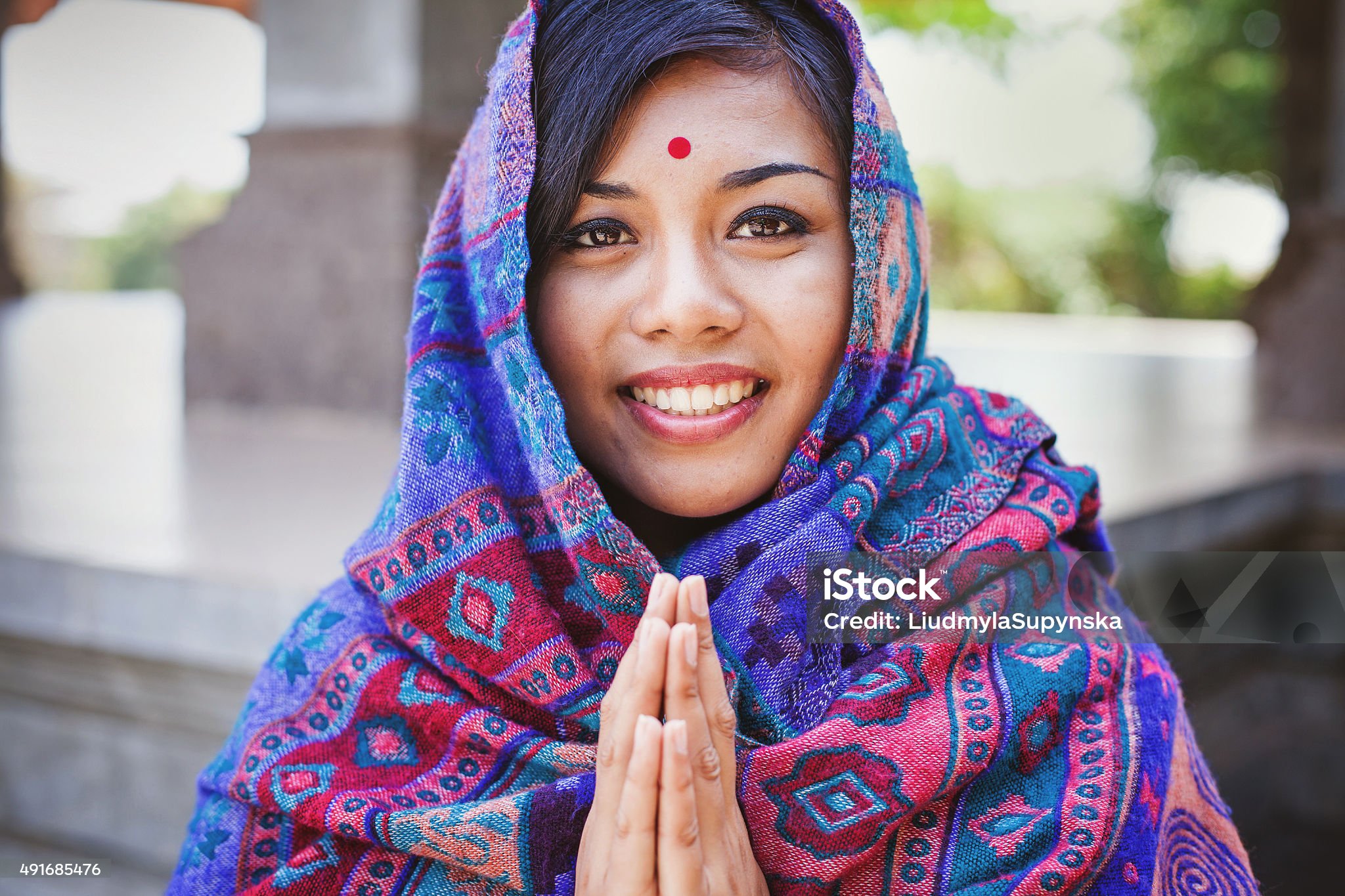 Young women in colored headscarf keepung her hands in "namaste"
